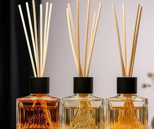Three glass reed diffuser bottles with natural rattan sticks and amber-golden fragrance oil, stylish home aromatherapy accent for living room or bedroom decor