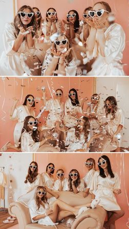 Bachelorette party: group of women in matching satin robes and white heart-shaped sunglasses blowing confetti and posing on a pink backdrop in a cozy indoor studio.