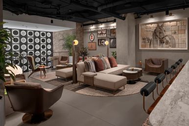 Stylish urban lounge with a beige sectional and striped pillows, leather armchairs, marble bar with leather-back stools, glowing circular wall panels and large framed horse artwork.