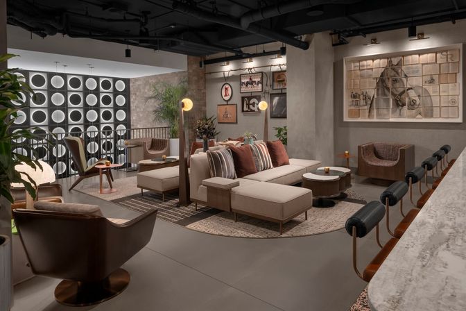 Stylish urban lounge with a beige sectional and striped pillows, leather armchairs, marble bar with leather-back stools, glowing circular wall panels and large framed horse artwork.