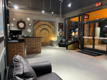 Escape room reception with wooden check-in desk, antique clock wall art, leather lounge chairs and glass double doors