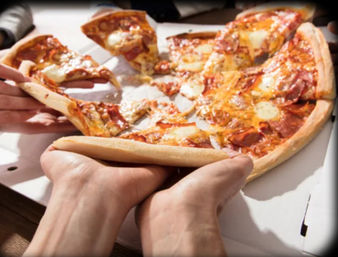 Hands pulling gooey pepperoni and mozzarella pizza slices from an open takeout pizza box on a table