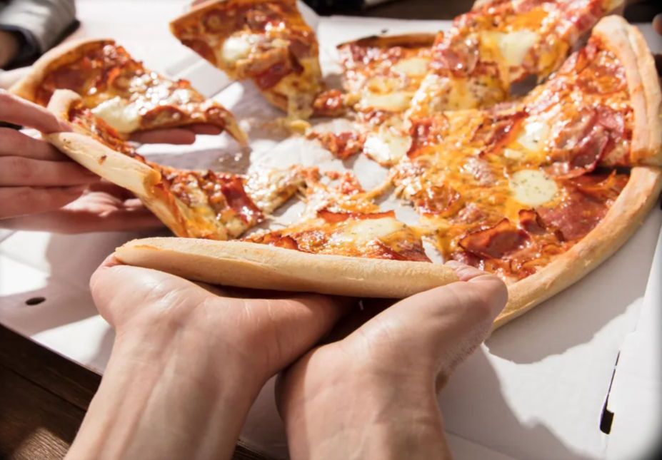 Hands pulling a hot pepperoni pizza slice with gooey melted cheese from a delivery pizza box