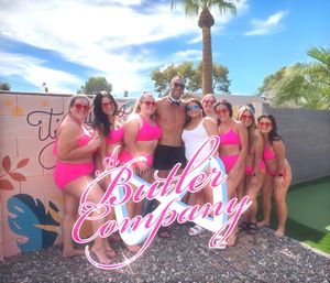 Sunny backyard pool party: group in matching hot-pink swimsuits and a shirtless man in a bow tie pose by a colorful mural and palm tree.