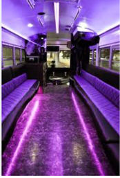 Luxury party bus interior bathed in purple LED lights, long bench seating along both sides, glittering floor and mirrored ceiling — ready to party.