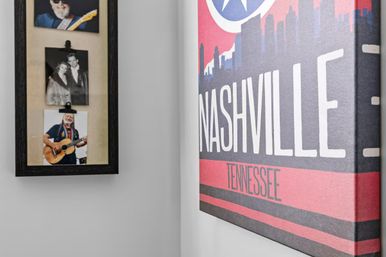 Music-themed wall with a colorful "Nashville, Tennessee" canvas print beside a black-framed collage of vintage musician photos on a white wall