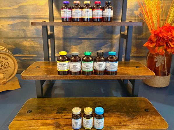 Tiered wooden shelf displaying amber supplement vials with colorful caps, small wooden barrel and bright orange floral arrangement — wellness display
