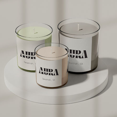 Three minimalist scented candles in clear glass jars—pastel green, blush, and gray—arranged on a white round display stand under soft natural light, modern tabletop home decor.