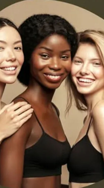 Studio portrait of three smiling women with varying skin tones in black camisoles posing closely against a neutral beige backdrop — diverse beauty and skincare concept.