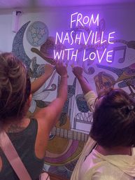 Three people seen from behind raising fists toward a purple neon sign reading "FROM NASHVILLE WITH LOVE" over a colorful guitar-and-music-note mural