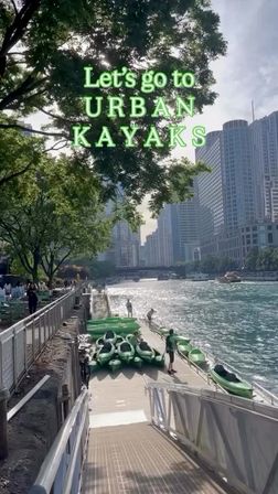 Green kayaks lined up on a riverfront dock with a person launching into a sunny downtown waterway, leafy trees and high-rise skyline; text overlay invites a kayak outing.
