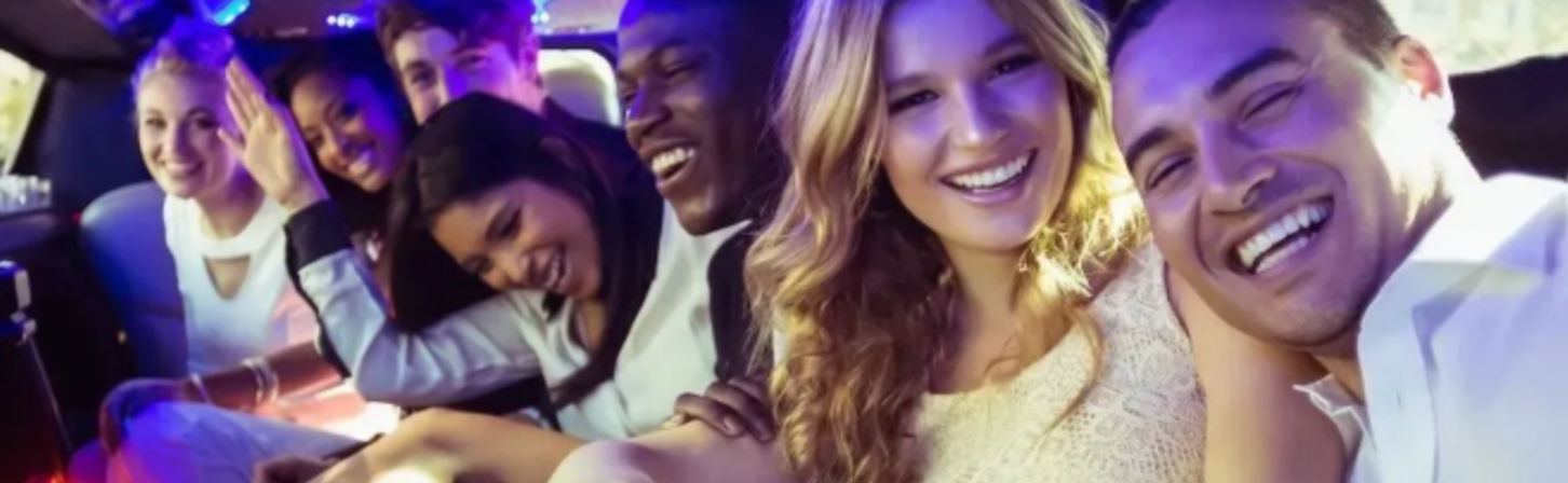 Six friends laughing and posing inside a stretch limousine with colorful party lights, enjoying a night out.