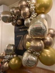 Glamorous gold and champagne metallic balloon garland arch with reflective cube and round balloons, indoor event decor for a stylish party backdrop