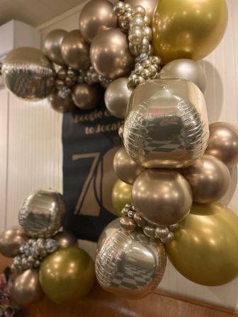 Glamorous gold and champagne metallic balloon garland arch with reflective cube and round balloons, indoor event decor for a stylish party backdrop