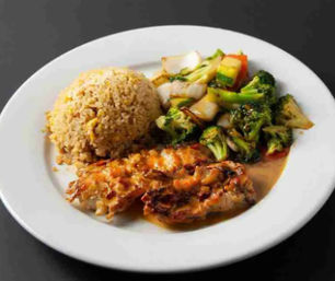 Glazed grilled chicken with fried rice and colorful stir-fried vegetables (broccoli, carrots, onions) on a white plate — savory Asian-style meal