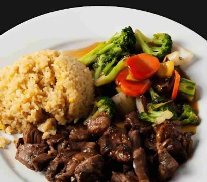 Colorful restaurant-style beef stir-fry: savory bite-sized beef in brown sauce, a mound of brown rice, and steamed mixed vegetables (broccoli, carrots, bell pepper, onion) on a white plate