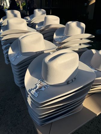 Rows of sunlit white felt cowboy hats stacked on an outdoor western market display.