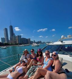 Six friends relaxing on a yacht on Lake Michigan with the Chicago skyline and high-rise buildings in the background, sunny blue sky and dozens of pleasure boats nearby