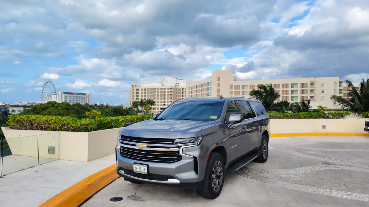 Silver Chevrolet SUV parked on a rooftop deck overlooking palm trees, resort hotels and a distant Ferris wheel beneath a partly cloudy blue sky.