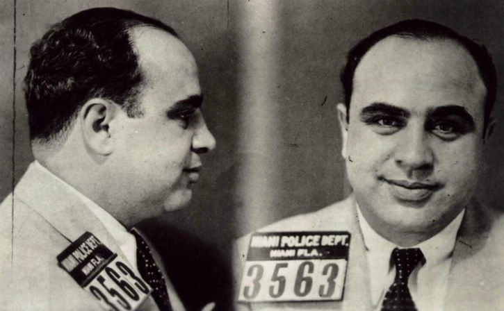 Vintage black-and-white double-profile mugshot of a man in a suit, front and side views, holding ID placard #3563 with 'Miami' partially visible.