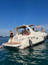 Group of friends on a white motor yacht anchored off Chicago, IL, lounging, sunbathing and swimming on a sunny summer day