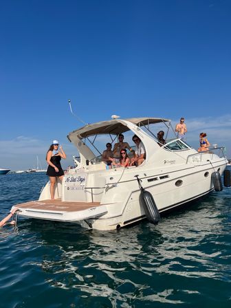 Group of friends on a white motor yacht anchored off Chicago, IL, lounging, sunbathing and swimming on a sunny summer day