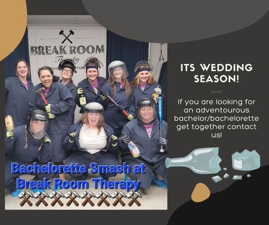 Smiling bachelorette party group wearing protective coveralls, face shields and gloves, holding bats and bottles after an indoor smash room session