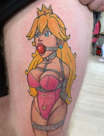 Color thigh tattoo of a gagged cartoon princess in pink lingerie and bondage straps, stylized pinup with crown and long blonde hair.