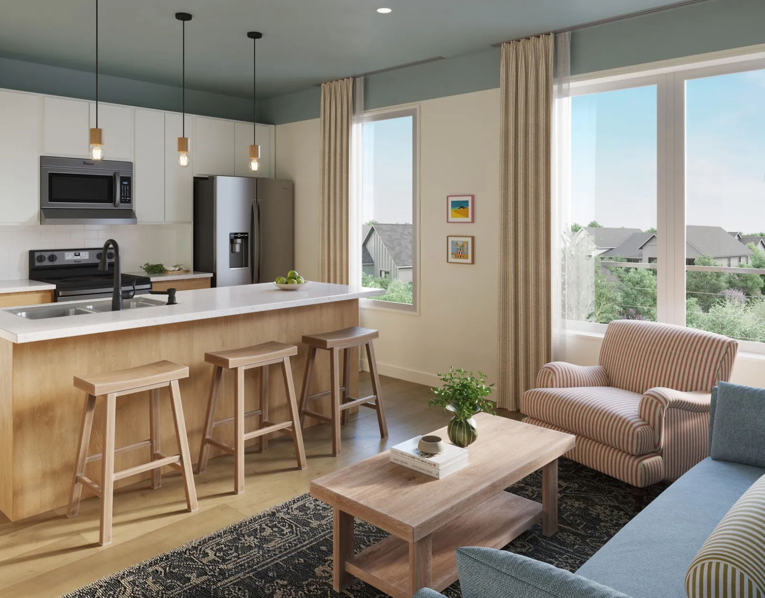 Bright modern open-concept kitchen and living area with white quartz island and three wooden bar stools, stainless steel appliances, pendant lights, large windows overlooking suburban greenery, striped armchair, blue sofa and light wood coffee table.
