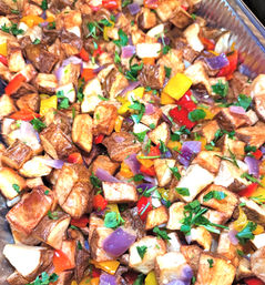 Roasted diced potatoes with colorful bell peppers, purple onion and chopped parsley served in an aluminum catering tray