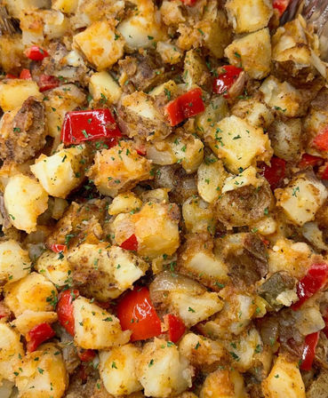 Crispy golden-brown breakfast potatoes (home fries) with diced red bell pepper, sautéed onions and parsley, seasoned roasted potato cubes