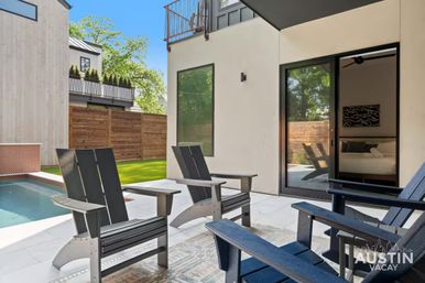 Sunny Austin modern backyard patio with dark Adirondack chairs by a narrow plunge pool, sliding glass door to a bedroom and wood privacy fence