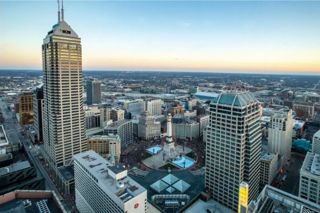 Aerial view of downtown Indianapolis at sunset, Monument Circle with the Soldiers and Sailors Monument and glowing fountains surrounded by skyscrapers