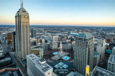 Aerial view of downtown Indianapolis at sunset, Monument Circle with the Soldiers and Sailors Monument and glowing fountains surrounded by skyscrapers