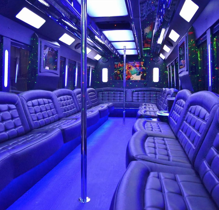 Interior of a luxury party bus with blue LED ambient lighting, tufted leather bench seats lining both sides, mirrored ceiling, disco laser lights, chrome dance poles — ready for a night out.