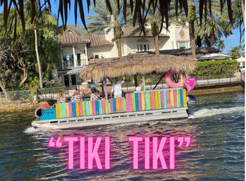 Colorful tiki-style pontoon boat with a thatched roof and pink float cruising a sunny tropical canal past palm trees and waterfront mansions, bright pink "TIKI TIKI" text overlay