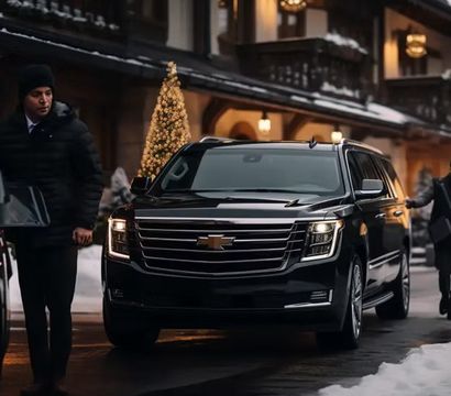Black luxury SUV parked outside a snow-covered alpine lodge at dusk, warm holiday lights and a decorated Christmas tree, valets and guests in winter coats