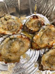 Baked oysters on the half shell with garlic butter, melted cheese and crispy breadcrumbs in a foil tray — savory seafood appetizer