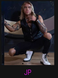 Edgy studio portrait of a tattooed person with shoulder-length blonde hair squatting on a wooden floor, wearing a black leather vest, ripped black jeans, white lace-up boots and layered necklaces against a dark backdrop with purple “JP” initials below.