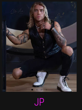 Edgy studio portrait of a tattooed person with shoulder-length blonde hair squatting on a wooden floor, wearing a black leather vest, ripped black jeans, white lace-up boots and layered necklaces against a dark backdrop with purple “JP” initials below.