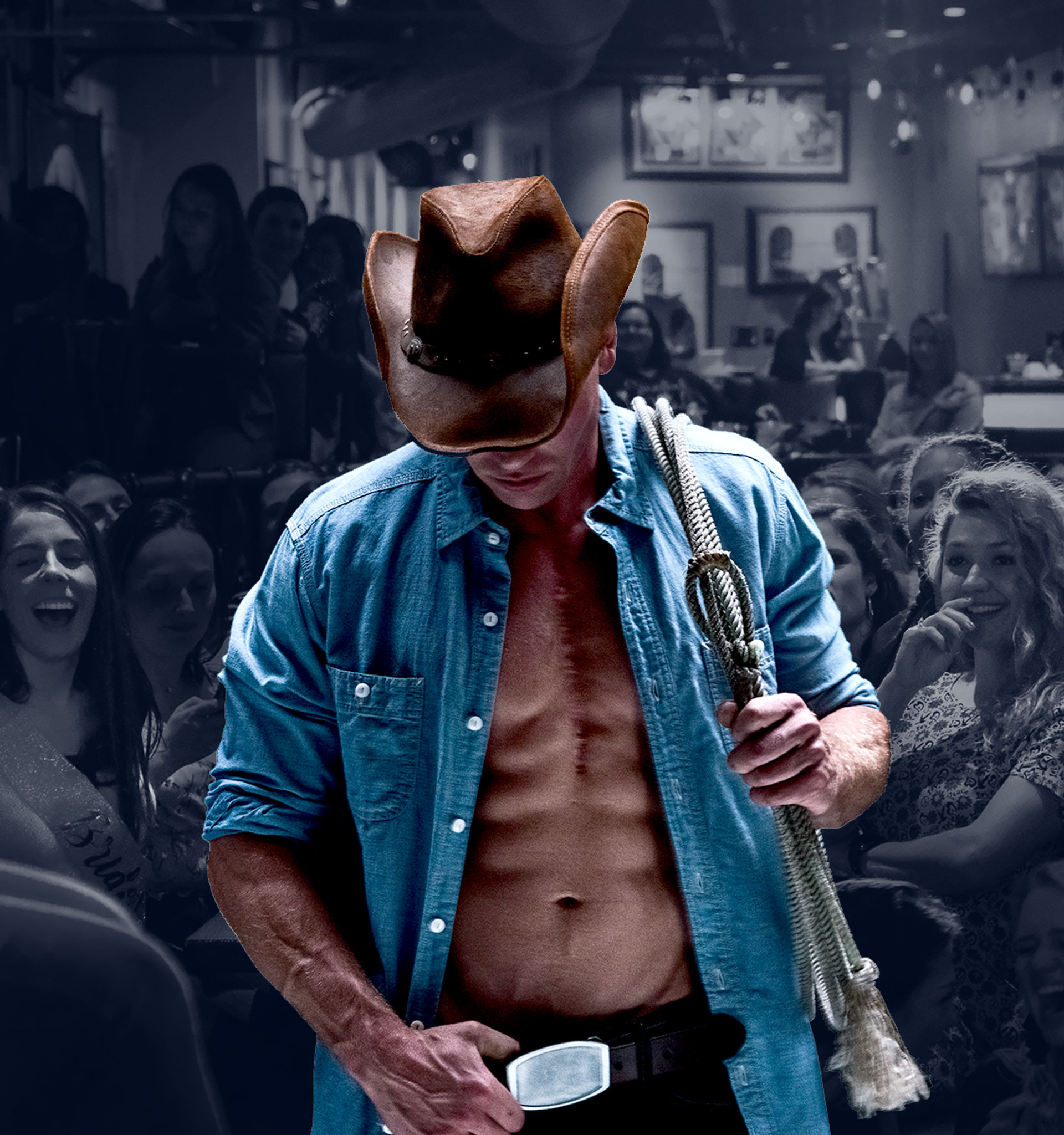 Muscular cowboy performer in a brown hat and open denim shirt holding a lasso and belt buckle while entertaining a cheering crowd in a lively country bar