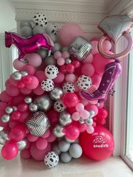 Bright pink and silver indoor balloon wall party backdrop with cow-print and metallic balloons, mirrored disco cubes, pink foil horse, cowboy boot and diamond ring balloons for a cowgirl-themed celebration