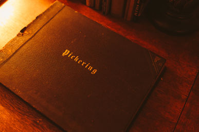 Cozy amber-lit scene of a vintage leather-bound book with gold lettering resting on a wooden desk