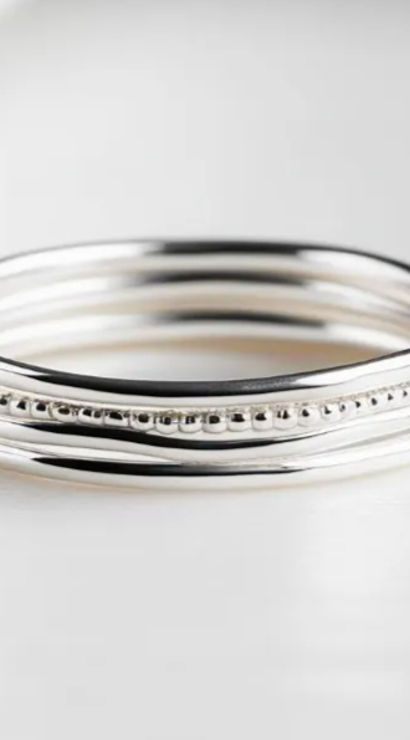 Close-up of three sterling silver stacking rings — smooth and beaded bands on a clean white background, minimalist jewelry product photo.
