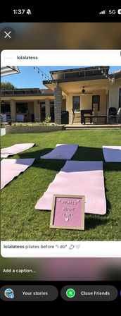 Backyard patio scene with pink Pilates mats on a green lawn and a small letterboard reading Pilates before I do, string lights and patio seating for an outdoor pre-wedding workout