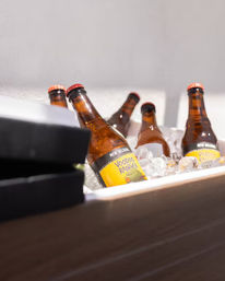 Chilled amber beer bottles with bright yellow Voodoo Ranger labels nestled in a white ice-filled cooler, ready for a gathering.