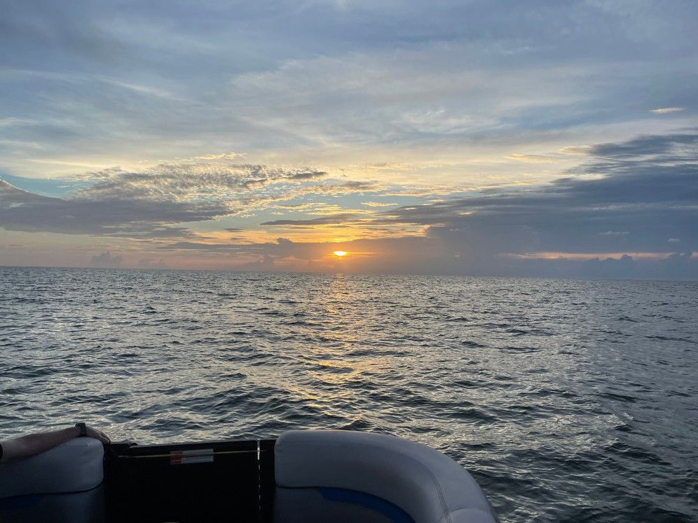 Golden ocean sunset seascape with rippling waves and cloudy sky, viewed from a boat's seating