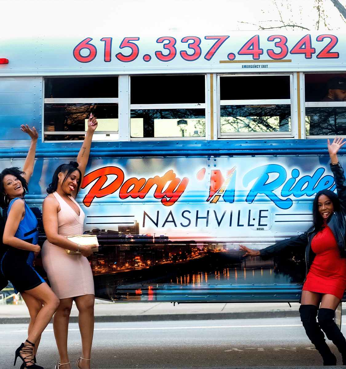 Three women in party dresses cheer and pose beside a colorful Nashville party bus decorated with skyline graphics and bright lettering at a city curb.