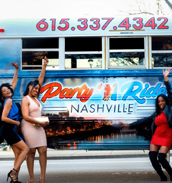 Three women in party dresses cheer and pose beside a colorful Nashville party bus decorated with skyline graphics and bright lettering at a city curb.