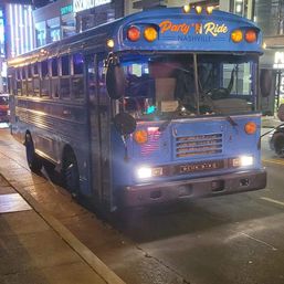 Retro blue party bus parked on a neon-lit downtown Nashville street at night